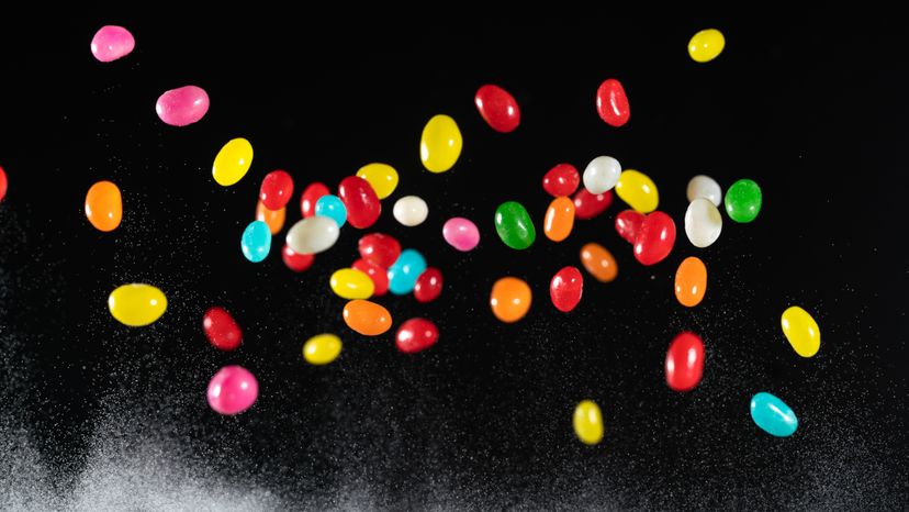 Jelly beans in the air against a black background. 