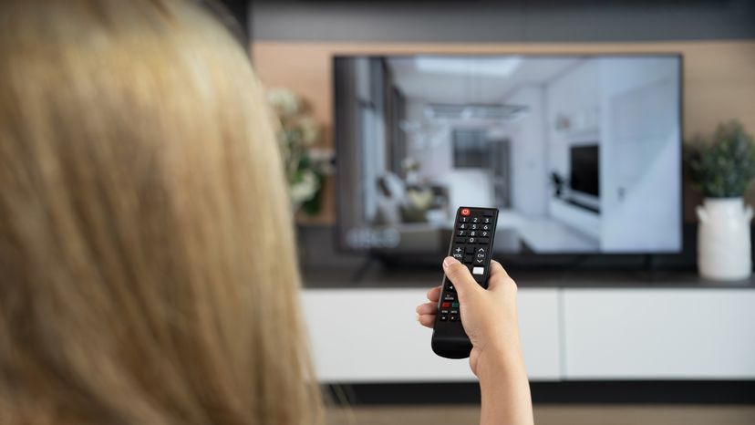 A woman sitting on a couch while watching Tv. 