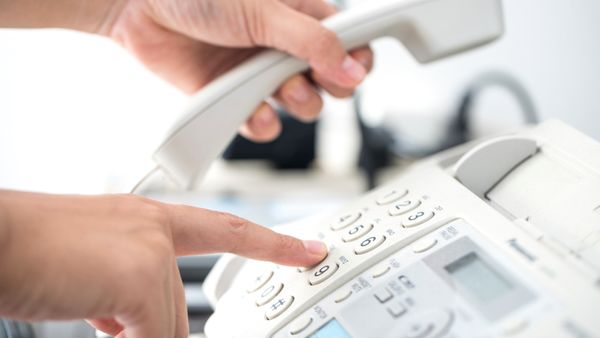 A mans hand holding up a telephones receiver. 