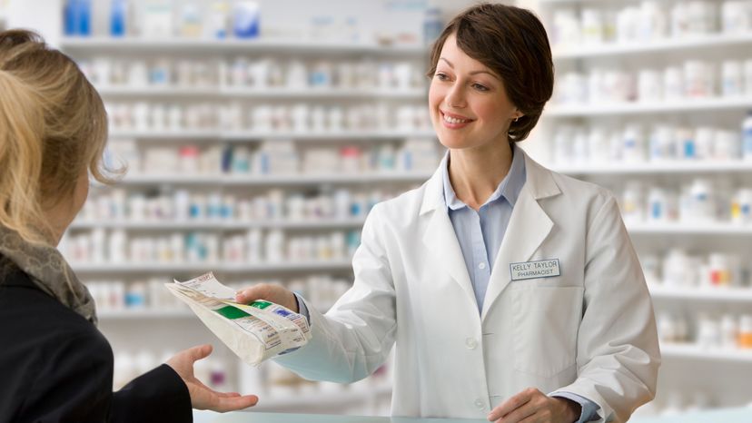 A pharmacist handing an elderly woman her drugs. 