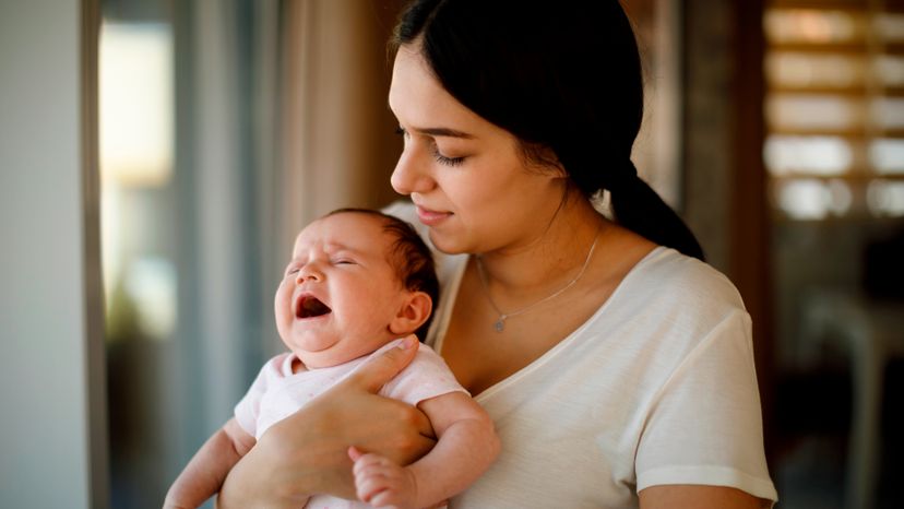 A woman holding a crying baby. 