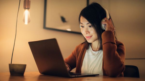 A woman watching a movie on her laptop with her headset on. 