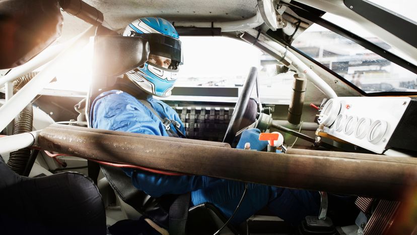 A race car driver in the drivers seat of a race car. 