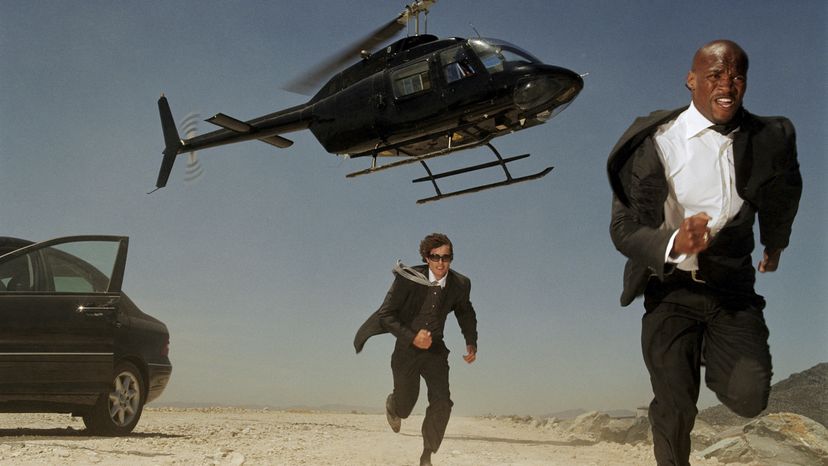 Two men running away from a helicopter. 