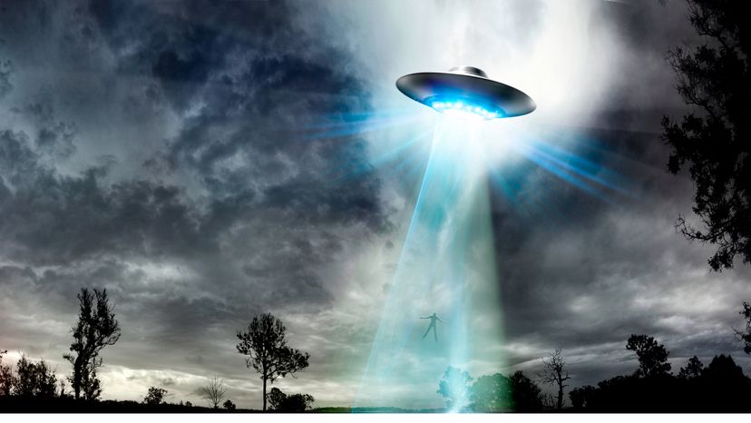 A UFO using a light beam to raise a man into the ship
