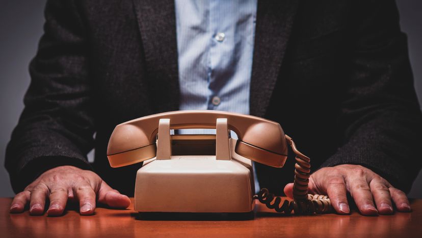 A man sitting in front of an analogue telephone 