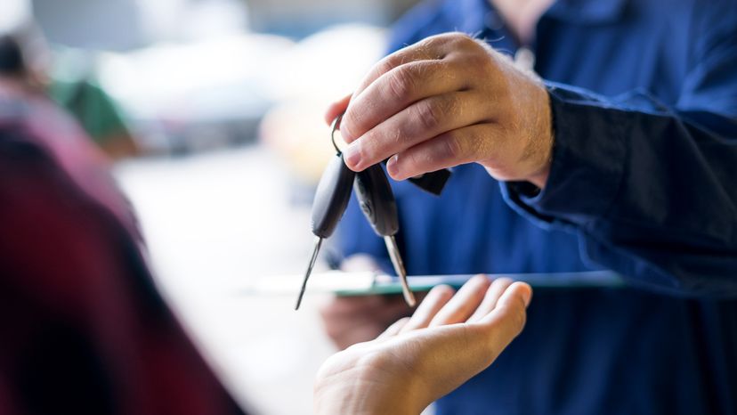 Car dealer handing over the car keys to the customer after purchase.