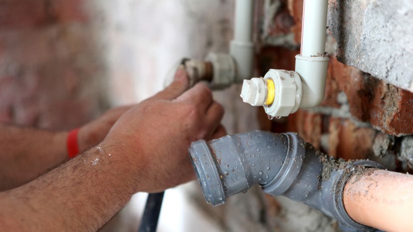 A repair man fixing a faulty pipe. 