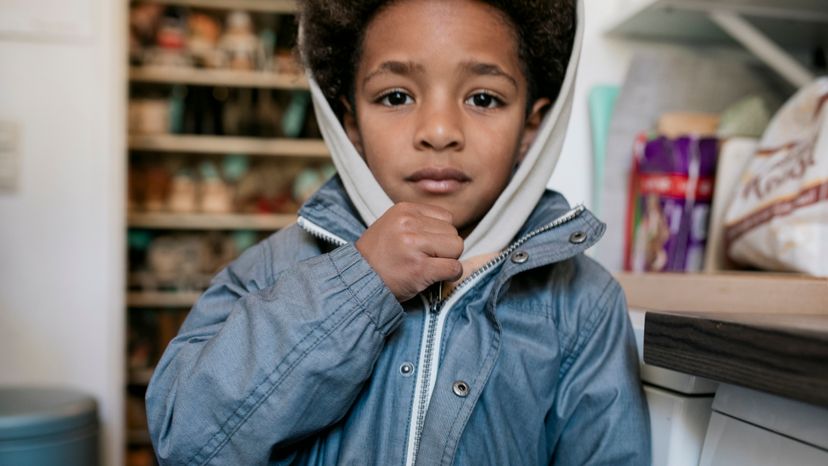 A little boy zipping up his jacket. 