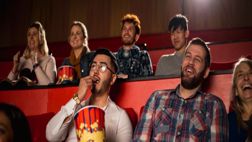 A group of people laughing in a movie theater. 