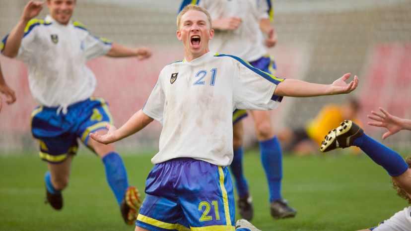 A soccer player kneeling on the field, celebrating a goal