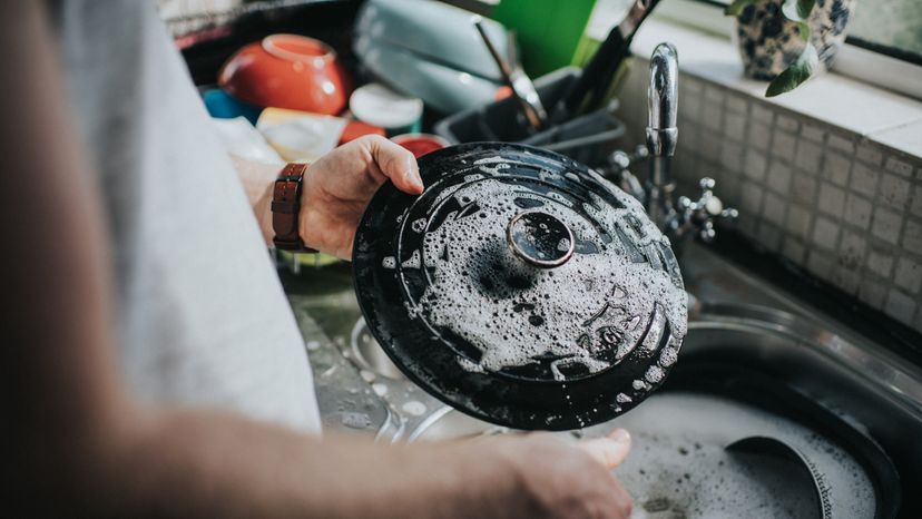 A man washing dishes in a sink. 