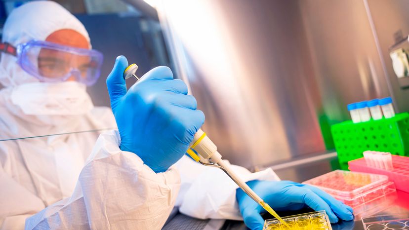 A scientist conducting an experiment in the lab while wearing protective gear. 