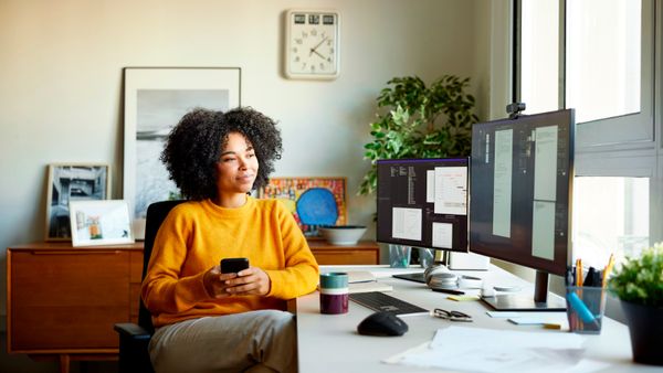 A woman sitting at her desk, looking at her computer's monitor. 