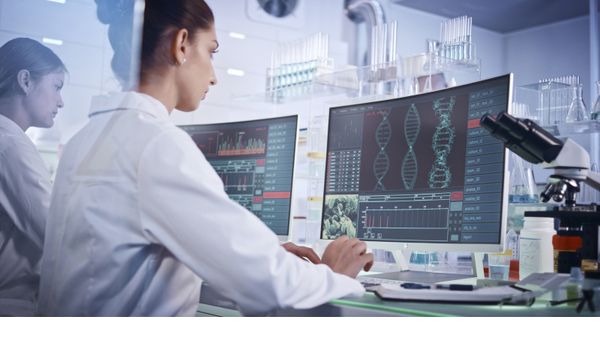 Scientist examining DNA models in a modern genetic research lab using a computer. 