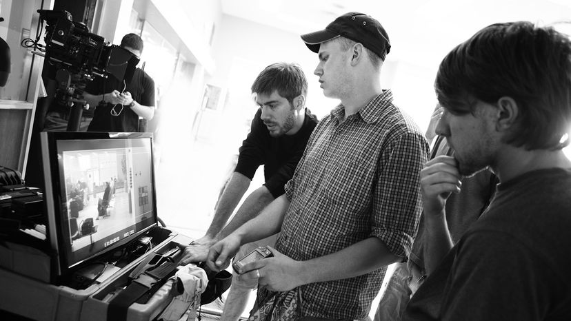 Director of photography, gaffer and director watching a take on the monitor.