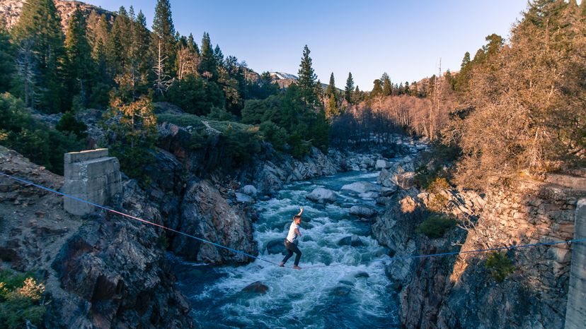 A man walking across a zip line. 