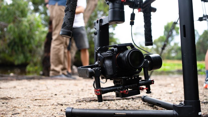 A camera attached to a gimbal, placed on the ground. 