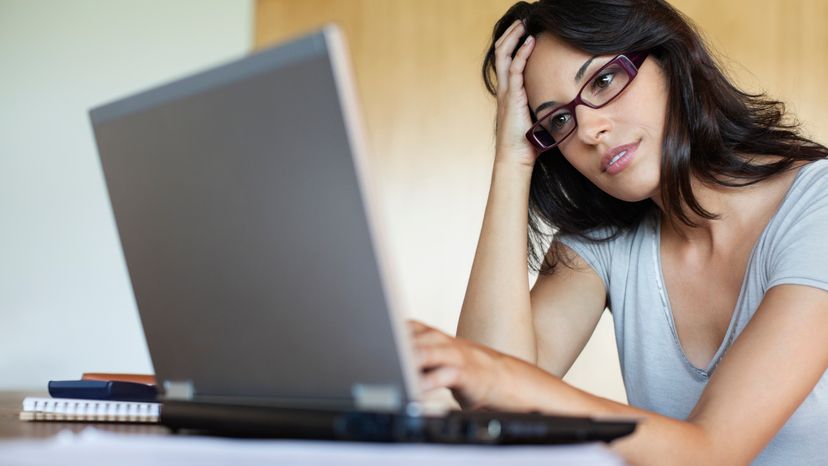 A woman sitting at a desk, using her laptop.