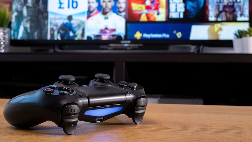 索尼Dualshock 4无线控制器与Playstation网上商店的电视屏幕后面＂width=