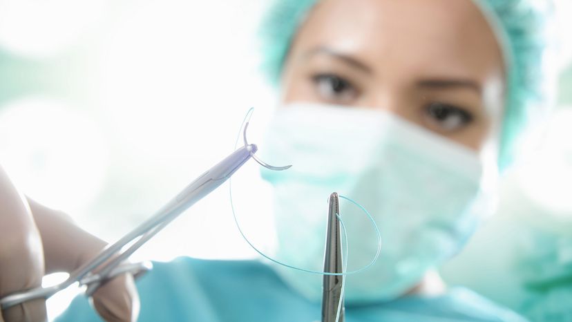 A surgeon stitching a patient. 