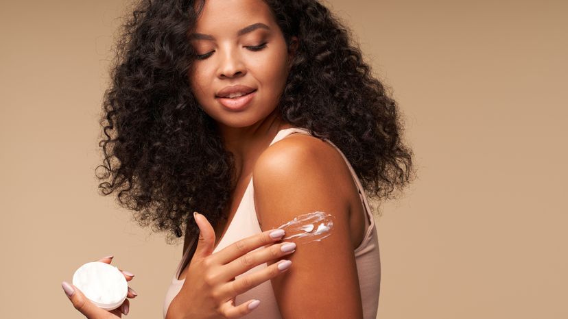 A woman applying moisturizer on her shoulder. 