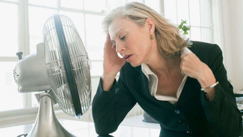 A woman sitting in front of a portable fan. 