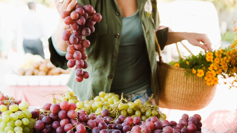 A woman buying grapes at the market. 