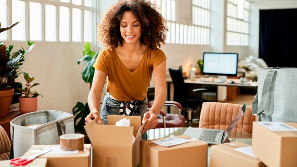 A young business woman packing boxes at home. 