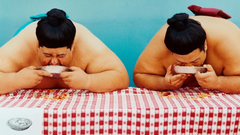 Two sumo wrestlers in an eating competition.