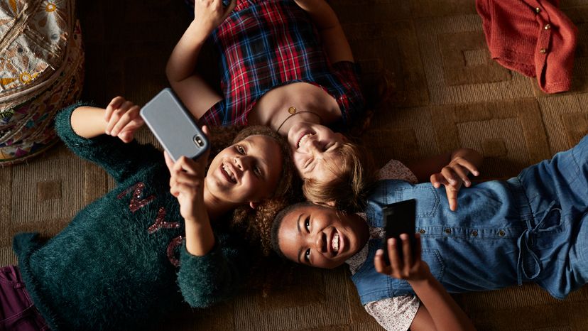 Three teenagers laying down while using their mobile phones. 