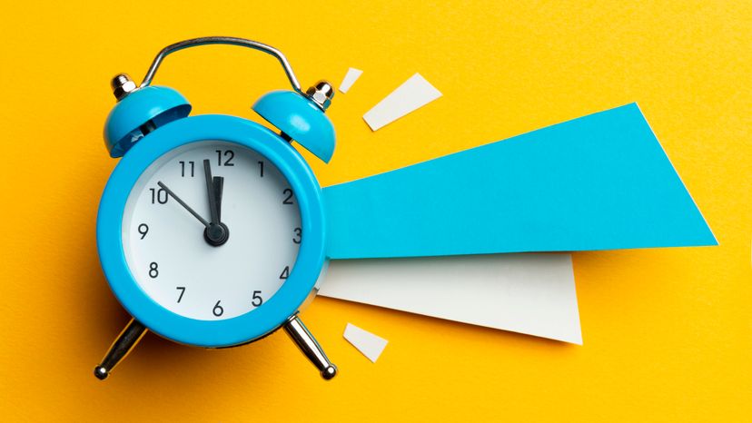 A blue alarm clock on a yellow background