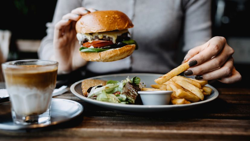 A woman with a plate of burger and fries. 