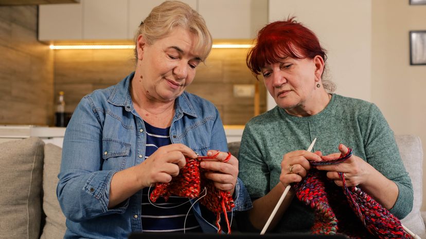 Two elderly women learning how to knit. 