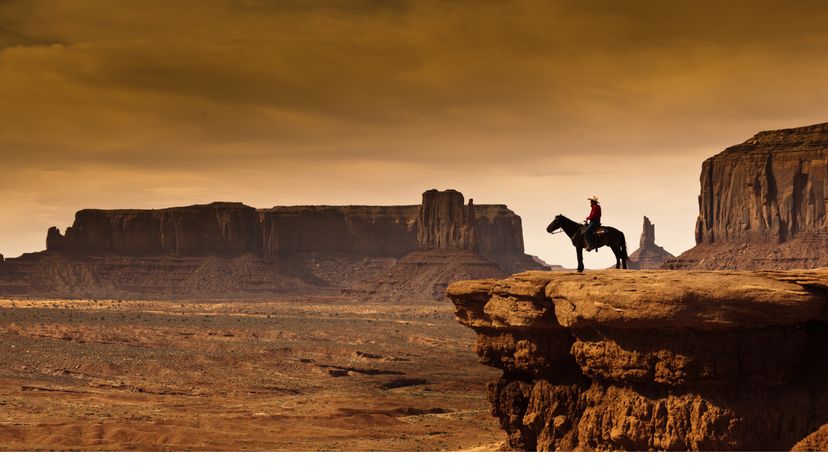 A cowboy on horseback at the edge of a cliff. 