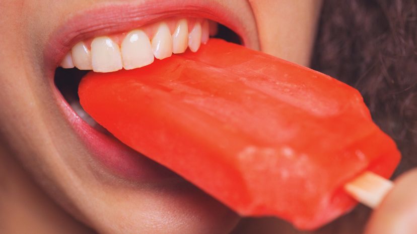 A woman licking a popsicle. 
