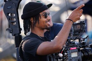 A camera operator smiles while filming at fairgrounds.