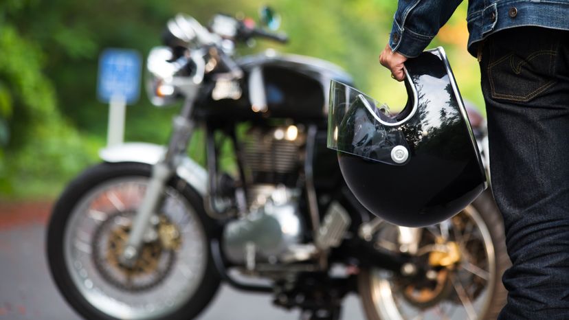 Hand man holding a helmet and  motorcycle blur background.