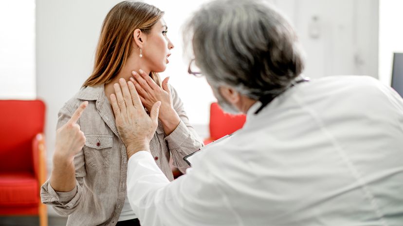 A young woman having her throat checked by a doctor. 