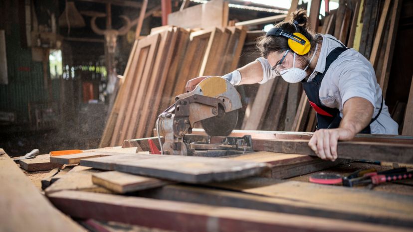 A carpenter using a saw to cut wood. 