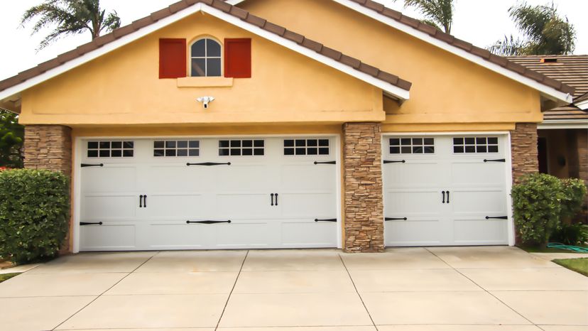 A yellow single-story home with carriage-style garage doors.