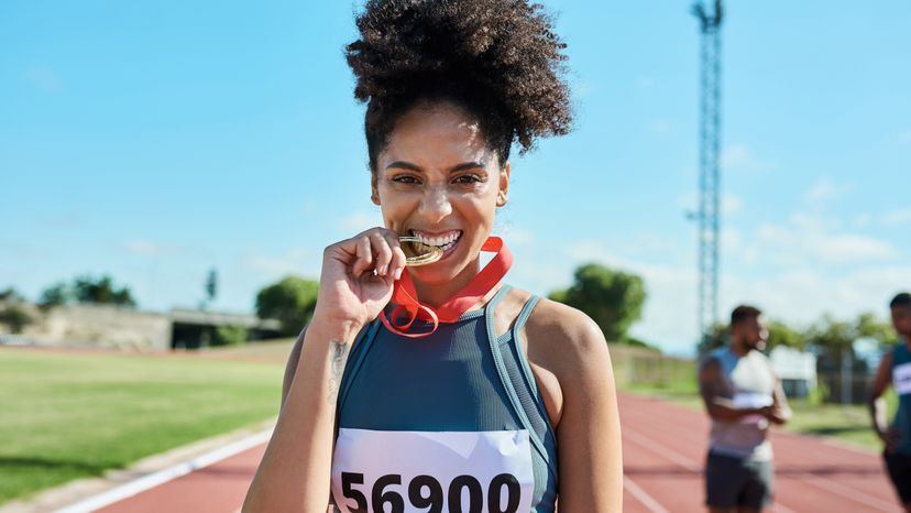 A female athlete biting her medal after winning. 