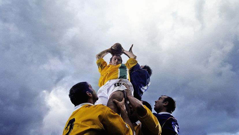 Football players gathered around a player holding the football in the air. 