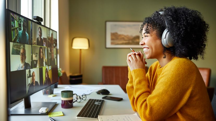 Businesswoman with headphones smiling during video conference.