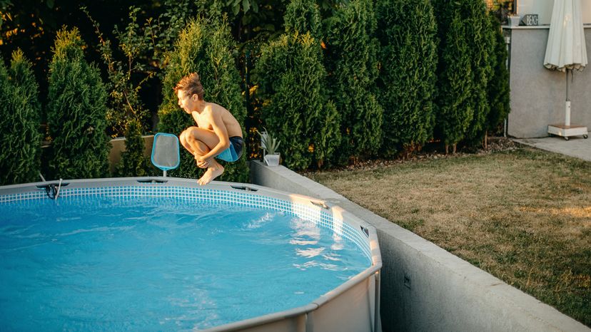 A young boy playing in an above ground pool. 