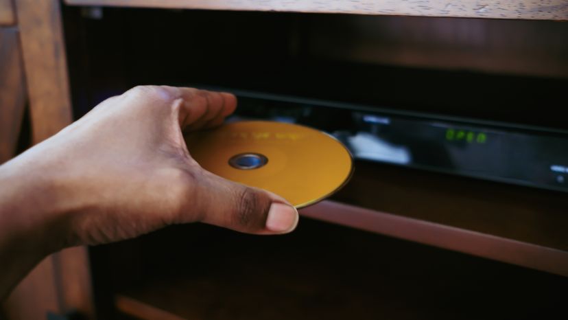 A close up of a woman inserting a disk into a DVD player. 