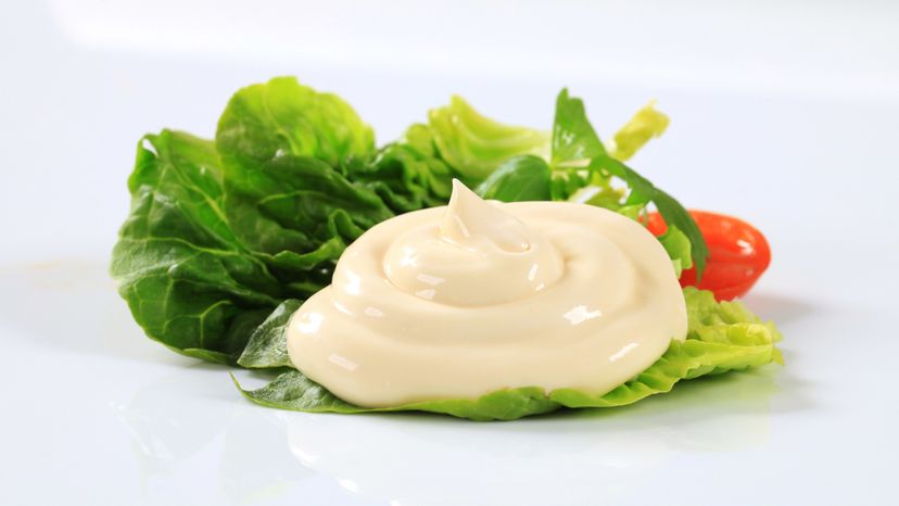 A lettuce leaf with tomatoes and mayonnaise on top. 