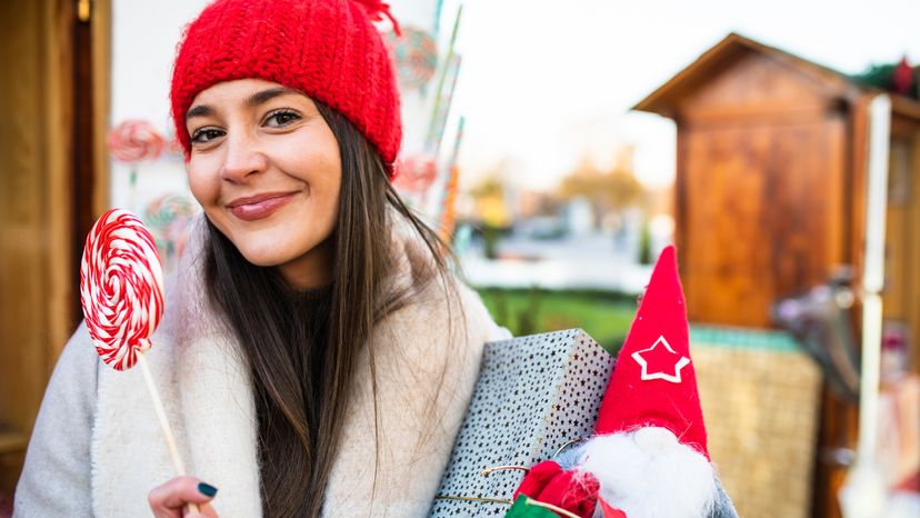 A young woman wearing a red hat while enjoying a Christmas bazaar. 