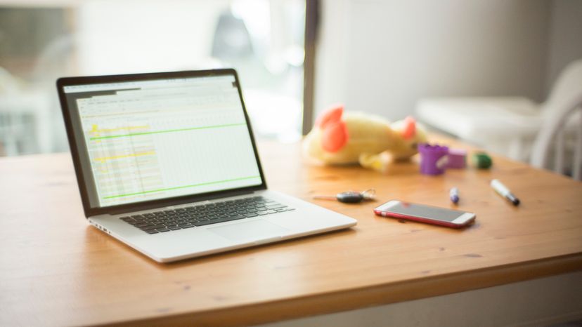 Laptop on a table with keys, toys and a mobile device. 