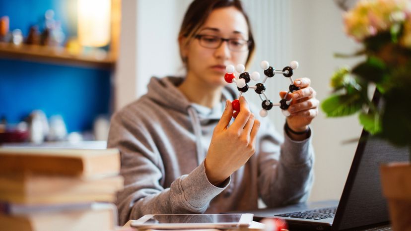 A student learning at home with a model of a molecule. 